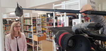 Die Fotos zeigen Impressionen vom Filmdreh in der Ernst-Abbe-Bücherei. Zu sehen ist ein Kameramann, der zwischen den Bücherregalen ein Interview führt.