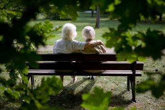 Zwei ältere Menschen sitzen auf einer Bank in der Natur