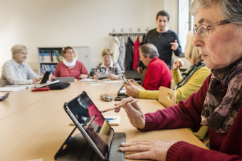 Seniorinnen und Senioren erhalten eine Schulung zum Umgang mit dem Tablet