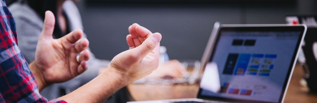 Menschen sitzen vor Laptops in einer Besprechung 