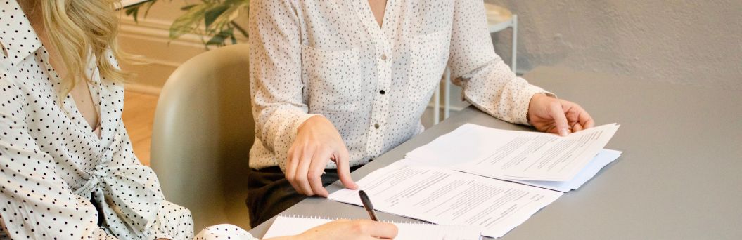 Zwei Frauen sitzen mit Formularen am Schreibtisch